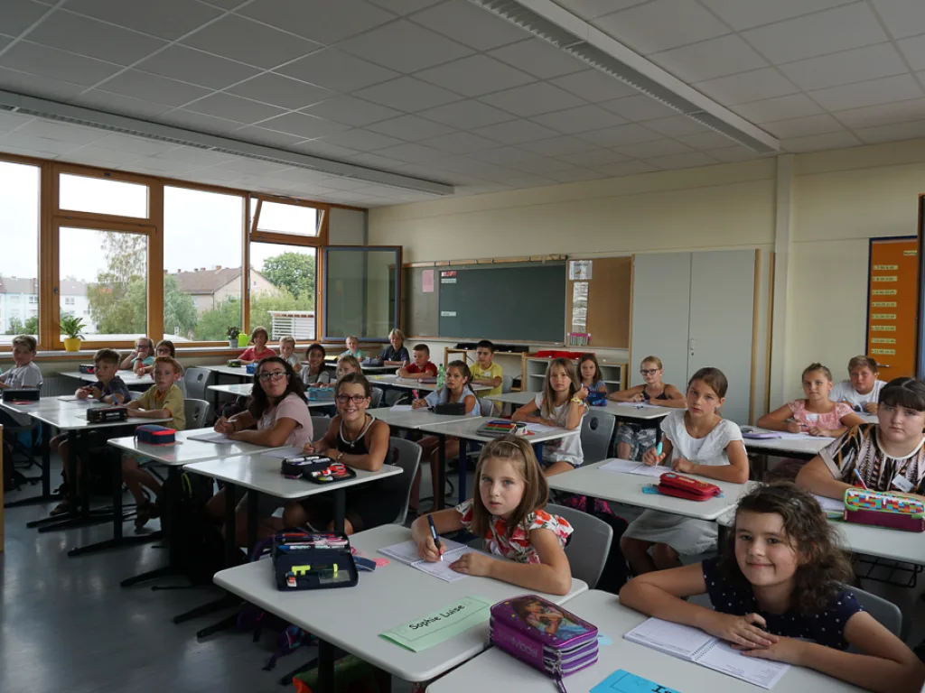 Kinder sitzen an ihren Plätzen im Klassenraum.